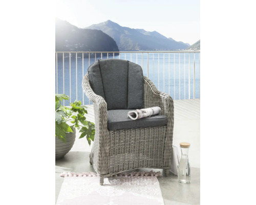 Fauteuil de jardin tressé avec coussins gris sur un balcon clair avec vue sur le lac et les montagnes.