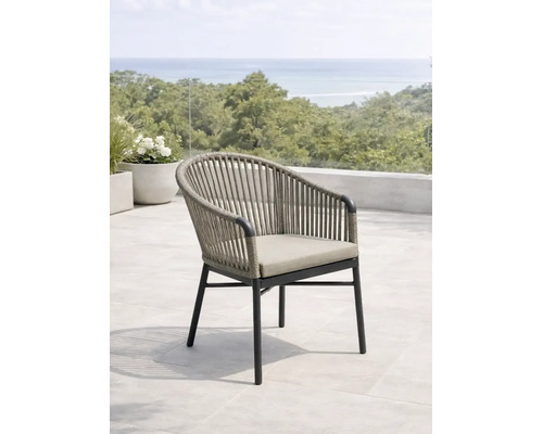 Moderner Gartensessel mit Seilbespannung und Sitzkissen auf einer hellen Terrasse mit Blick ins Grüne und auf das Meer.