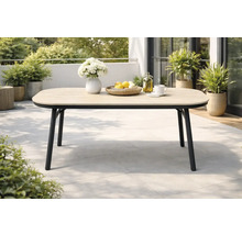 Table de jardin moderne sur une terrasse avec plateau en aspect bois et structure en métal noir, entourée de plantes.