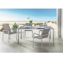 Ensemble mobilier de jardin moderne avec table rectangulaire et quatre chaises sur terrasse vue mer. Table avec plateau foncé et cadre en métal.