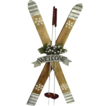 Dekorative Wanddekoration aus gekreuzten Holzskiern mit Welcome-Banner, Schneeflocken-Motiven und Tannenzweigen.