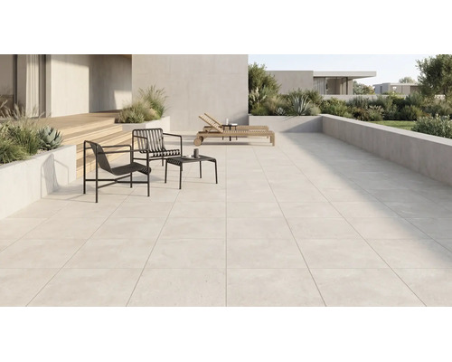 Grosszügige moderne Terrasse mit hellen Terrassenplatten, schwarzen Metallsesseln, Beistelltisch, Holzliegen und bepflanzten Betonkübeln.