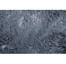 Nahaufnahme der Textur eines Hochflor-Teppichs mit zotteliger Oberfläche.
