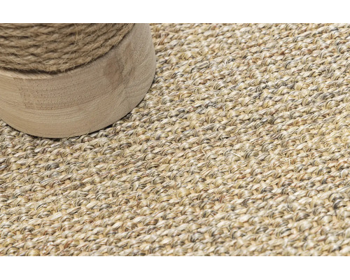 Detailaufnahme eines gewebten Teppichs aus Naturfasern mit einem runden Möbelfuß aus Holz und Seilwicklung.