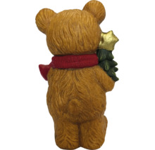 Rückansicht einer Weihnachtsfigur in Bärenform mit rotem Schal, die einen kleinen Weihnachtsbaum mit goldenem Stern hält.