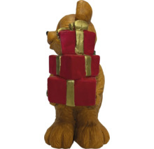 Weihnachtsfigur kleiner brauner Bär hält einen Stapel roter Geschenke mit goldfarbenen Bändern.
