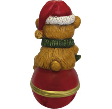 Rückansicht einer Weihnachtsfigur Teddybär mit roter Weihnachtsmütze und grünem Schal auf einer roten Glocke.