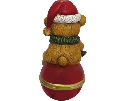 Rückansicht einer Weihnachtsfigur Teddybär mit roter Weihnachtsmütze und grünem Schal auf einer roten Glocke.