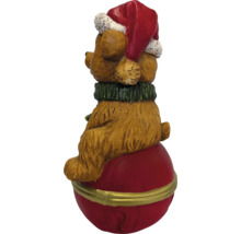 Weihnachtsfigur Bär auf roter Kugel mit Weihnachtsmütze und grünem Schal.
