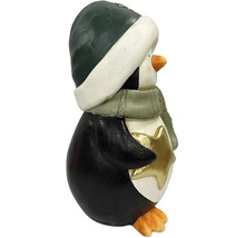 Dekofigur Pinguin aus Kunststein mit grüner Mütze, Schal und goldenem Stern, Winterdekoration.