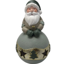 Figurine de Noël Père Noël assis sur une boule, avec barbe et bonnet, bande dorée avec découpes d'étoiles et sapin.