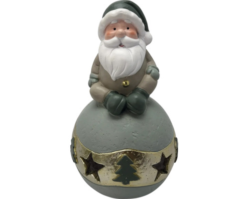 Figurine de Noël Père Noël assis sur une boule, avec barbe et bonnet, bande dorée avec découpes d'étoiles et sapin.