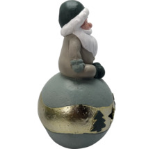 Figurine de Noël gnome assis sur une boule avec bande décorative et découpe en forme de sapin.