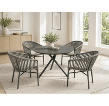 Salle à manger moderne avec une table ronde et quatre fauteuils en corde tressée avec coussins clairs dans une pièce lumineuse.