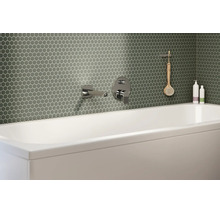 Salle de bain moderne avec mosaïque hexagonale verte au mur derrière une baignoire blanche avec robinetterie chromée.