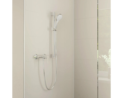 Ensemble de douche chromé avec douchette, barre de douche, flexible et mitigeur monocommande sur un mur carrelé clair.