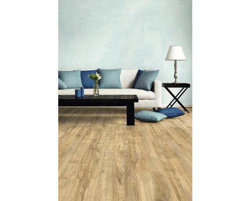 Salon moderne avec revêtement de sol clair aspect bois, canapé blanc avec coussins bleus et table basse noire.