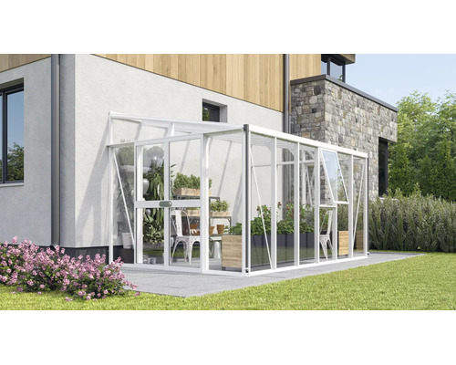 Serre adossée en aluminium et verre contre un mur de maison, avec porte coulissante et lucarne sur une terrasse avec des plantes de jardin.