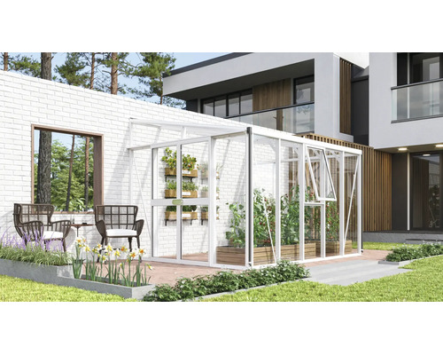 Serre adossée blanche en aluminium et verre contre un mur en briques blanches sur une terrasse moderne avec plantes et meubles de jardin.