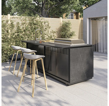 Moderne Outdoor-Kücheninsel mit Spülbecken, Grill und drei Barhockern auf einer gefliesten Terrasse vor einem Holzzaun.