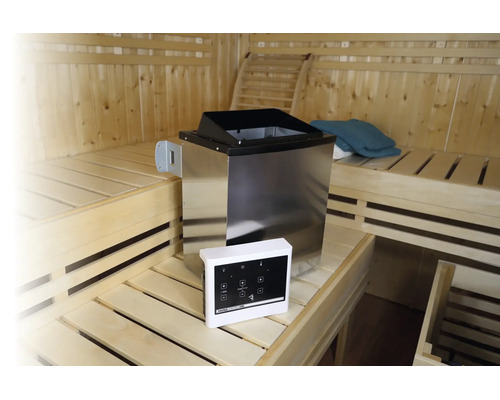 Poêle de sauna en acier inoxydable avec unité de commande numérique dans un sauna en bois avec des bancs sur plusieurs niveaux.