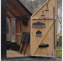 Hell und organisiert eingerichtetes Gartenhaus aus Holz mit Gartengeräten an der Tür sowie Klappstühlen und Pflanztöpfen im Inneren.