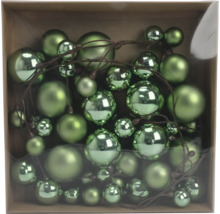 Grüne Weihnachtskugeln in verschiedenen Größen an einem Dekozweig, glänzend und matt, in einer Schachtel.