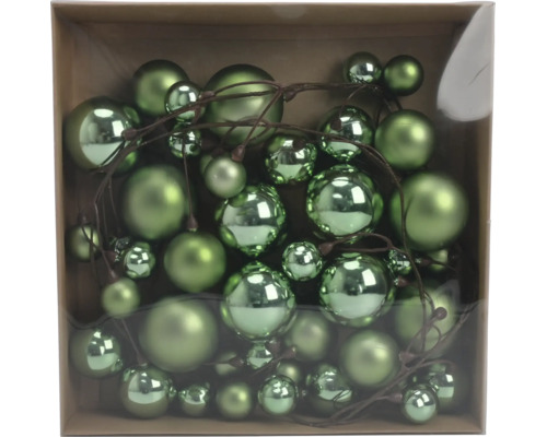 Grüne Weihnachtskugeln in verschiedenen Größen an einem Dekozweig, glänzend und matt, in einer Schachtel.