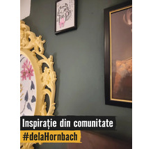 Dekorative Wandgestaltung mit verschiedenen Bilderrahmen auf einer dunkelgrünen Wand, inklusive eines großen, gelben, verzierten ovalen Rahmens.