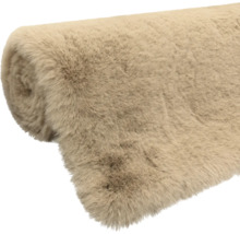 Aufgerollter Kunstfellteppich in Beige aus weicher Synthetikfaser.