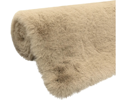 Aufgerollter Kunstfellteppich in Beige aus weicher Synthetikfaser.