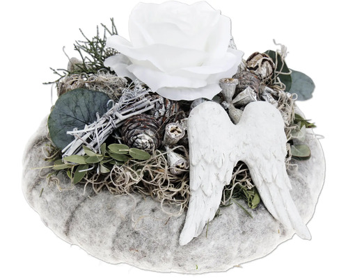 Composition funéraire avec rose blanche, ailes d ange et matériaux naturels comme des pommes de pin et du lichen sur un support rond.