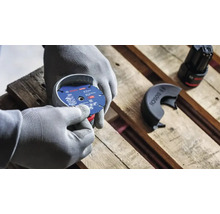Personne avec des gants de travail montant un disque à tronçonner Bosch Expert de 76 millimètres de diamètre sur une meuleuse angulaire sans fil.
