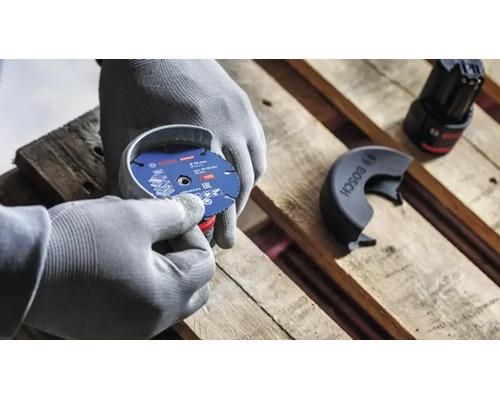 Personne avec des gants de travail montant un disque à tronçonner Bosch Expert de 76 millimètres de diamètre sur une meuleuse angulaire sans fil.