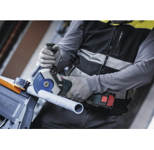 Artisan coupant un tuyau avec une meuleuse angulaire Bosch sans fil et portant des gants de protection