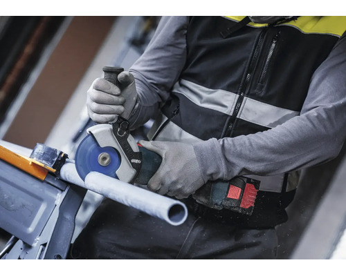 Artisan coupant un tuyau avec une meuleuse angulaire Bosch sans fil et portant des gants de protection