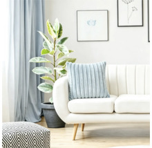 Un coussin douillet nervuré sur un canapé clair dans un salon lumineux avec une plante et un pouf géométrique.