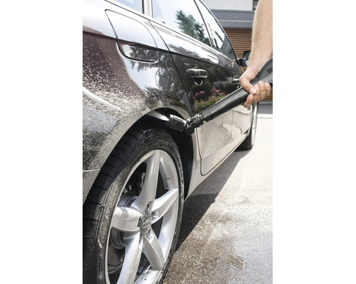 Une personne nettoie le passage de roue d une voiture avec un nettoyeur haute pression et une buse Kärcher spéciale pour l entretien automobile.