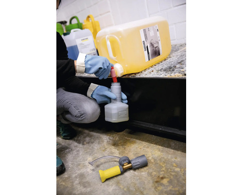 Person befüllt mit Schutzhandschuhen eine kleine Kärcher Flasche mit Reinigungsmittel aus einem großen Kärcher Kanister.