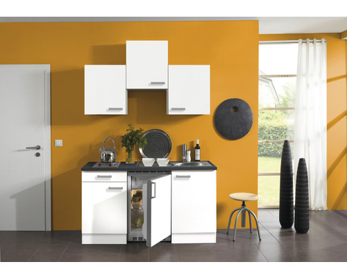 Cuisine compacte avec placards blancs, évier et réfrigérateur dans une pièce lumineuse.