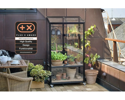 Pflanzenregal mit Glasabdeckung auf Rollen für den Balkon neben einem Gartentisch mit Stühlen und einem Plus X Award Siegel für Qualität.