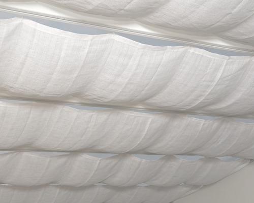 Vue détaillée d''un système de store pliant en tissu blanc sur une fenêtre