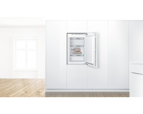 Integrierter Gefrierschrank mit offener Tür in einer weißen Küche