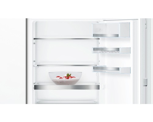 Innenansicht eines Kühlschranks mit Glasablagen und einer Schüssel mit Erdbeeren.