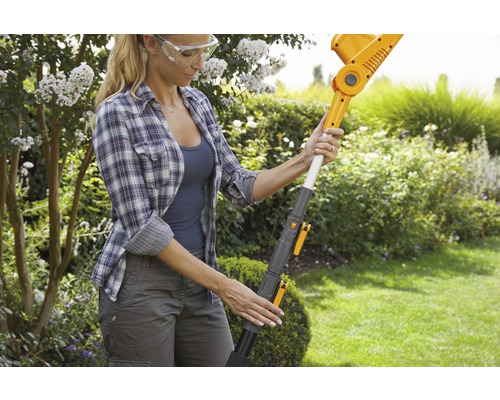 Une femme utilise un taille-haie sans fil dans le jardin.