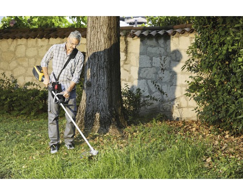 Mann verwendet einen Rasentrimmer im Garten.