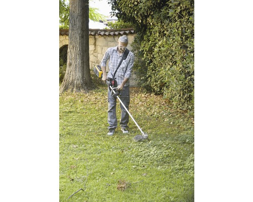 Mann benutzt einen Rasentrimmer im Garten.