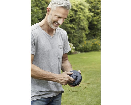 Mann hält Spule für Rasentrimmer in den Händen