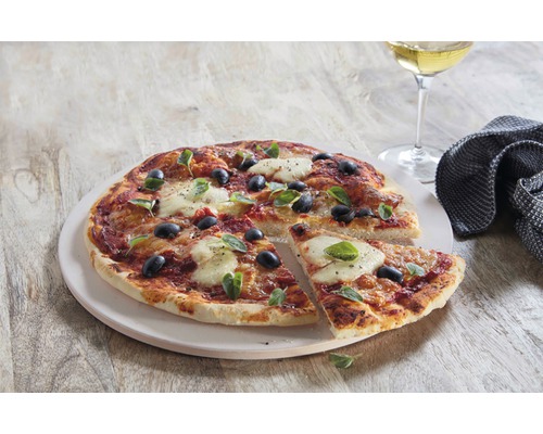 Pizza aux tomates, mozzarella, olives et basilic sur une assiette à pizza