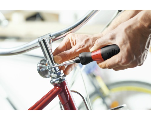 Une personne fixe une pièce de vélo avec un tournevis.